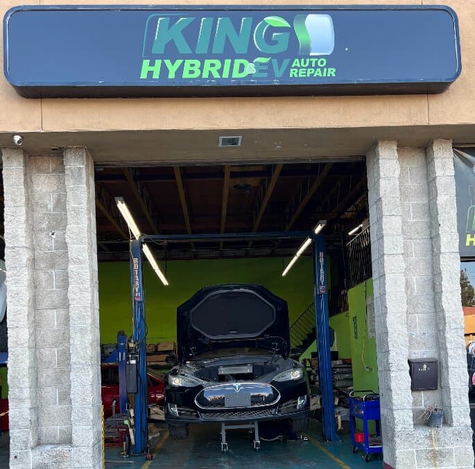 A Tesla Model S on a lift in a service bay at King of Hybrid & EV Auto Repair