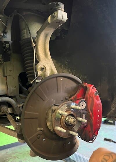 A Tesla wheel hub, rotor and caliper during brake work