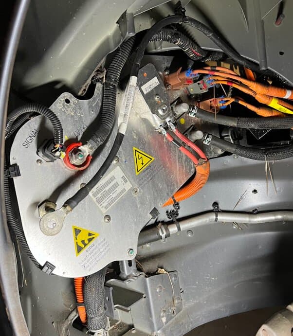 A Tesla high-voltage junction with orange high-voltage cables
